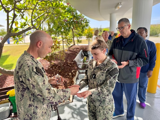 Naval Station Guantanamo Bay Staff Chaplain, Lt. Ben Pitre, blesses Lt. j.g. Grace Sedeu Nishevikj’s hands during a ceremony held at U.S. Naval Hospital Guantanamo Bay, May 13, 2025. The Blessing of the Hands is a traditional ceremony among healthcare workers that serves as a spiritual moment of reflection and renewal, recognizing that a nurse’s hands are instruments of compassion, comfort and care. (U.S. Navy photo by Emily McCamy/released)