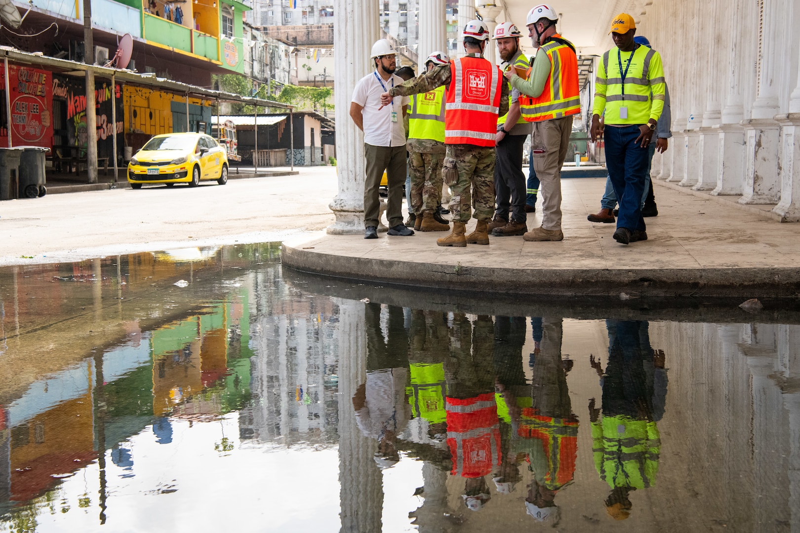 A group of men in reflective safety vests speak to each other.