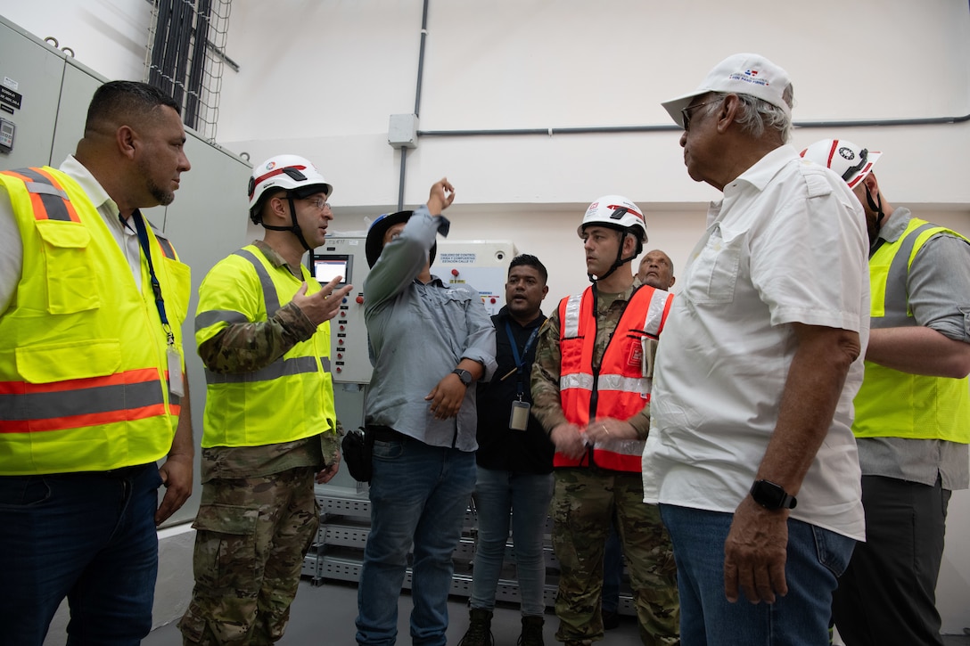 A group of men in reflective safety vests speak to each other.