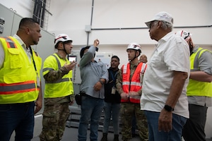 A group of men in reflective safety vests speak to each other.