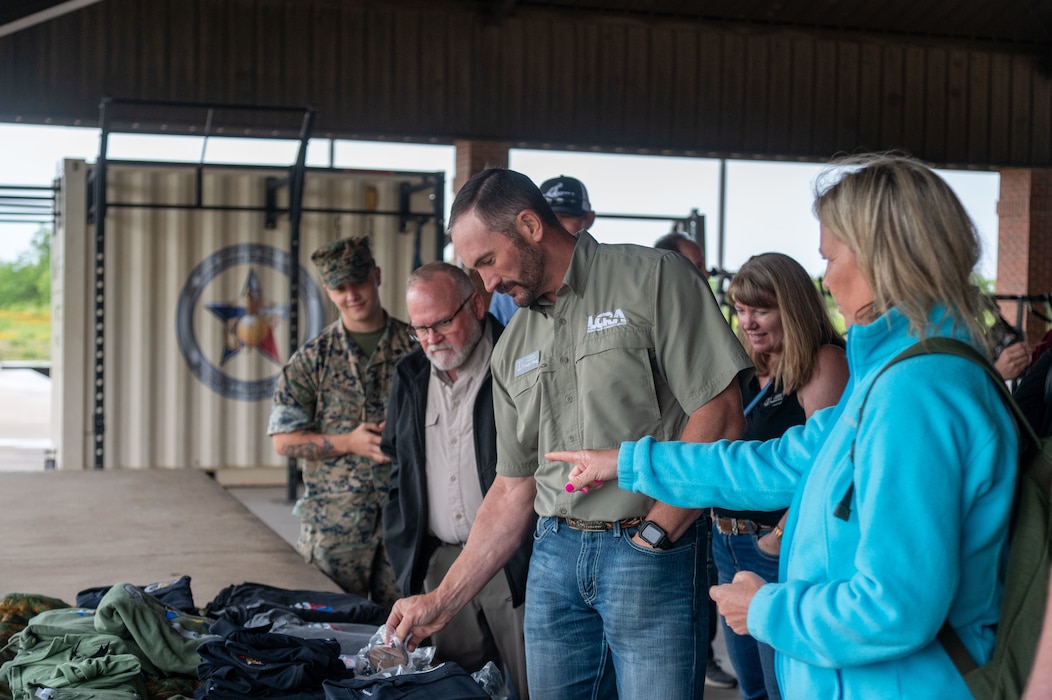 The 2024–2025 class of 17th Training Wing honorary commanders check out some U.S. Marine Corps swag following the Detachment Day visit at Goodfellow Air Force Base, Texas, May 8, 2025. Honorary commanders observed the Marines' high standards, disciplined approach, and expeditionary mindset that prepare them for real-world tactical and strategic operations in austere environments. (U.S. Air Force photo by Airman 1st Class James Salellas)