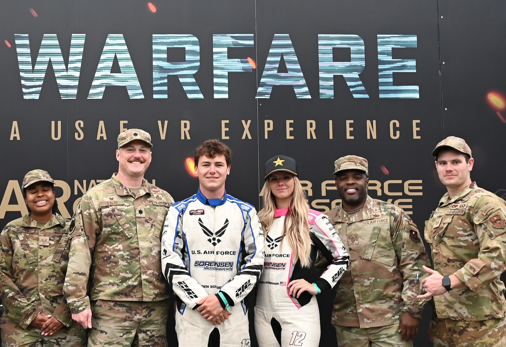 Branden and Amanda Sorensen, Air Force Recruiting Service, sponsored motorsports athletes pose for a photo with Airmen from the 331st Recruiting Squadron at Formula Drift Atlanta May 10,2025.