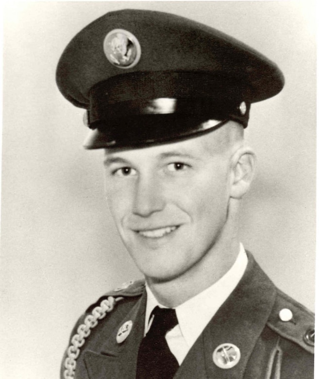 A man in uniform and cap smiles for a photo.