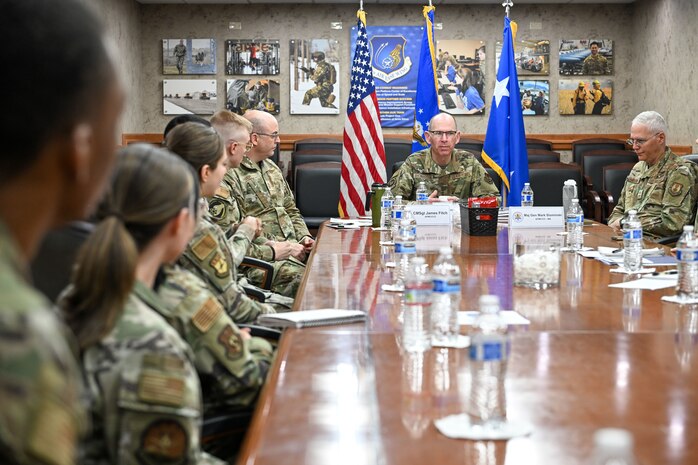 A group of military leadership and Airmen and civilians sitting around a conference table