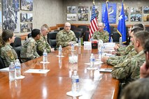 A group of military leadership and Airmen and civilians sitting around a conference table