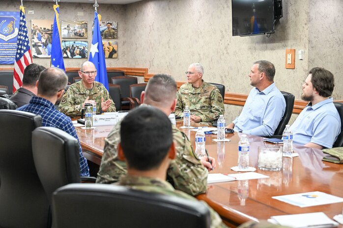 A group of military leadership and Airmen and civilians sitting around a conference table