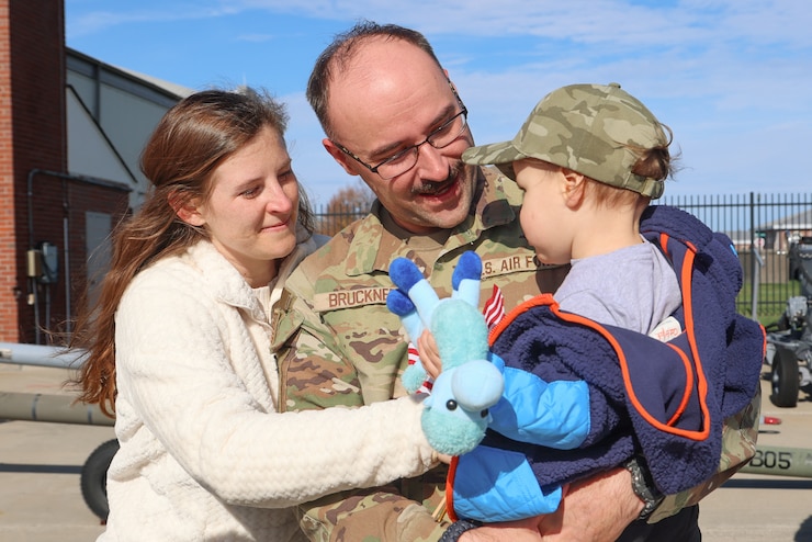 Female airman embracing children