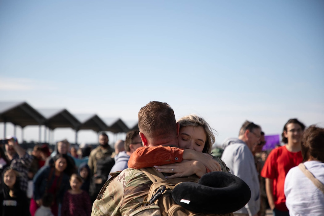 Uniformed members shaking hands and hugging loved ones.
