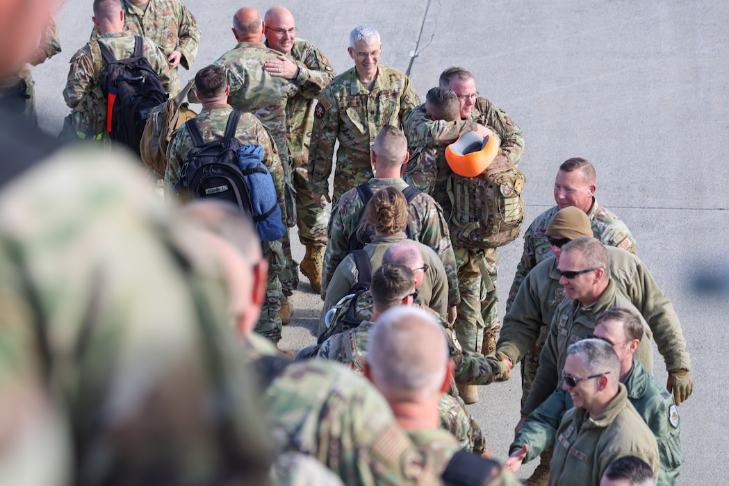 Uniformed members shaking hands and hugging loved ones.