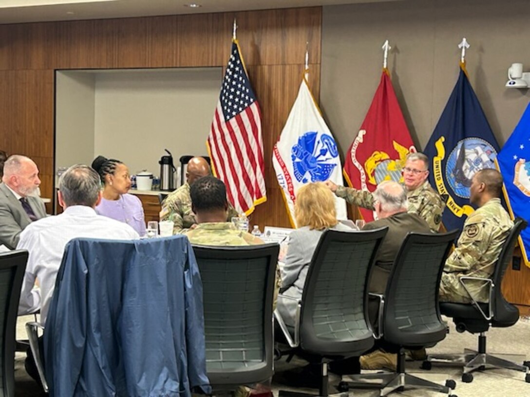 civilian and military men and women sit around conference table