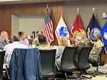 civilian and military men and women sit around conference table