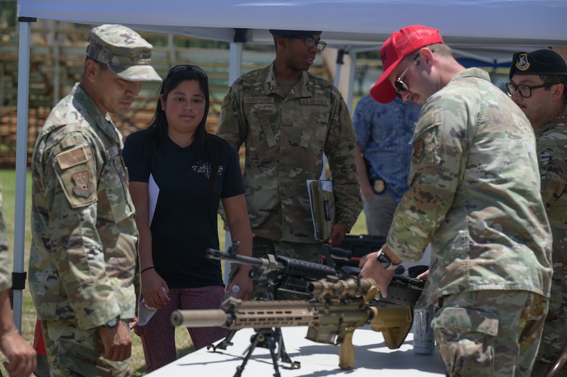 Airmen and civilians view security forces equipment on a table.