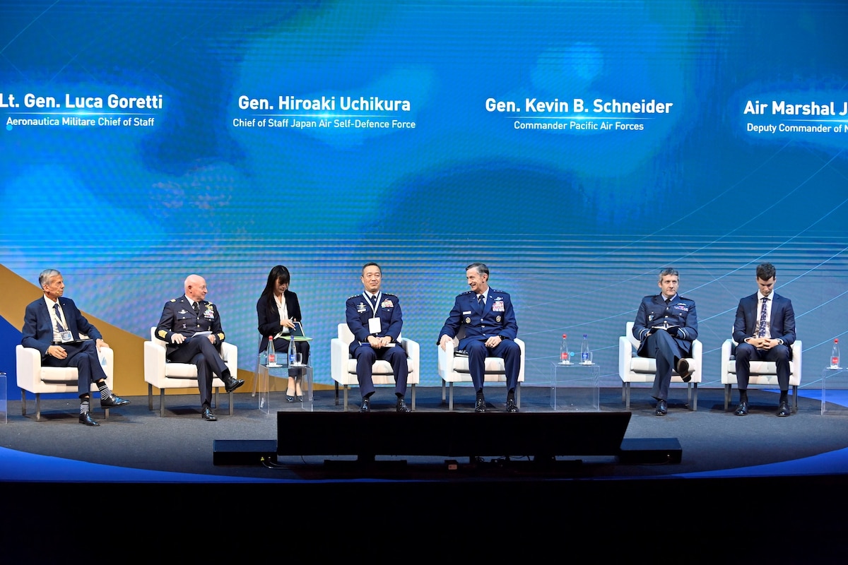 A group of people sit on a stage discussing.