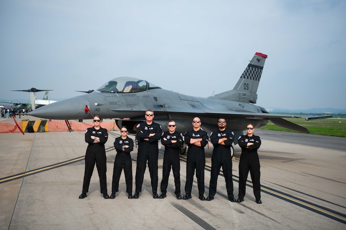military members pose in front of an F-16 fighter jet