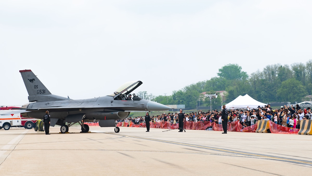 a large audience watches an F-16 aircrew launch a jet during an airshow