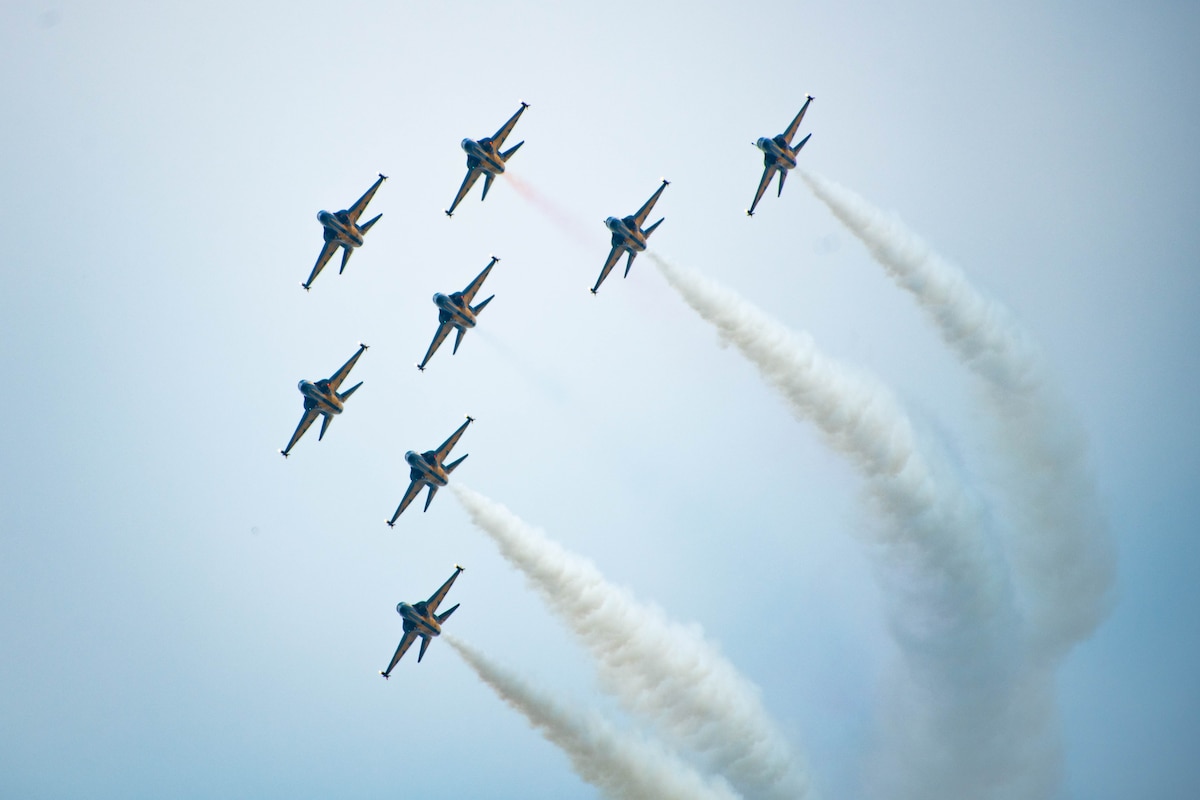 a formation flight of 8 jets turns across the sky