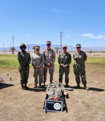From left, Cmdr. Christina Carter, HM2 Alvarez Kenyon, HM2 Mark Martin, HM2 Thalia Vasquez, and HM1 Hope Perrault pose for a photo while providing information about Navy Medicine careers to local high school students during a Military Occupational Specialty Exposition held May 1 at Marine Corps Air Ground Combat Center Twentynine Palms. Carter, Vasquez, and Perrault are assigned to Navy Medicine Readiness and Training Command Twentynine Palms, while Kenyon and Martin serve with 7th Marine Regiment. The event aimed to educate students about military career paths and highlight the role of Navy Corpsmen in both clinical and operational settings (U.S. Navy courtesy photo).