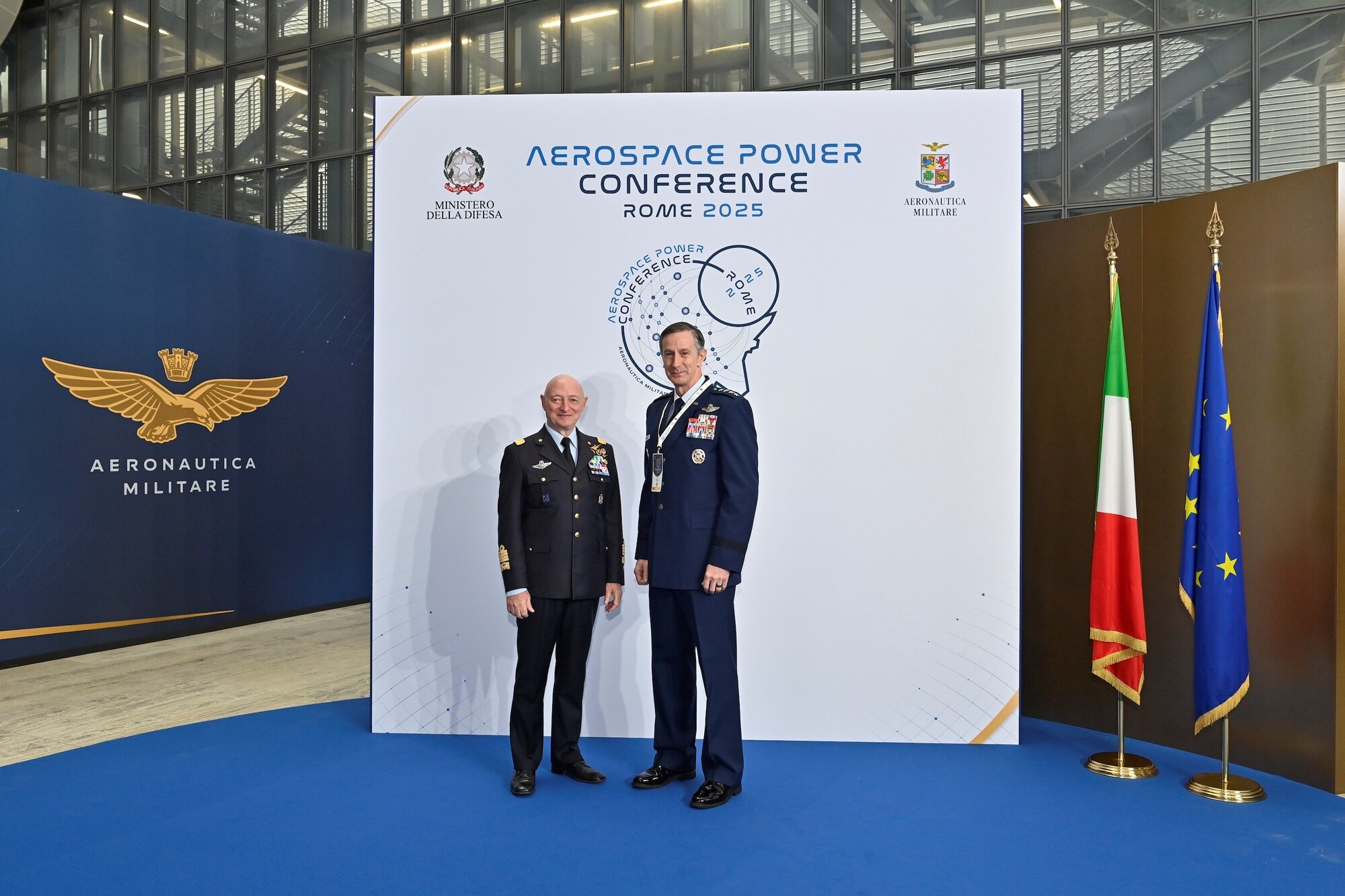 Two men stand together in front of a banner