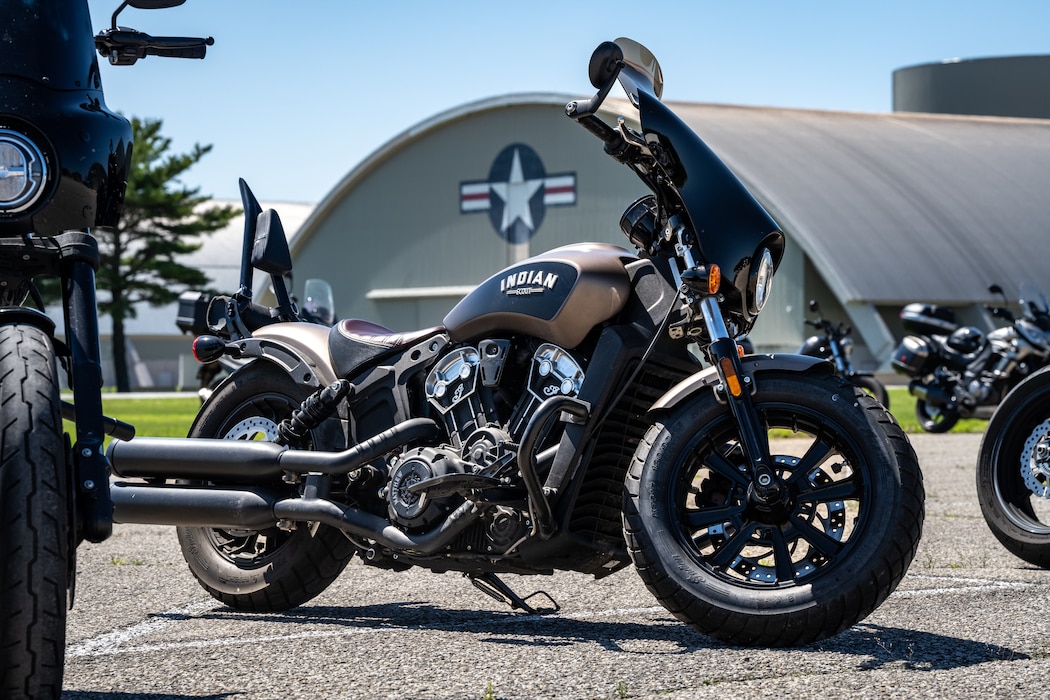 A bronze and black motorcycle stands in front of a large hangar with the Air Force star logo painted on the front