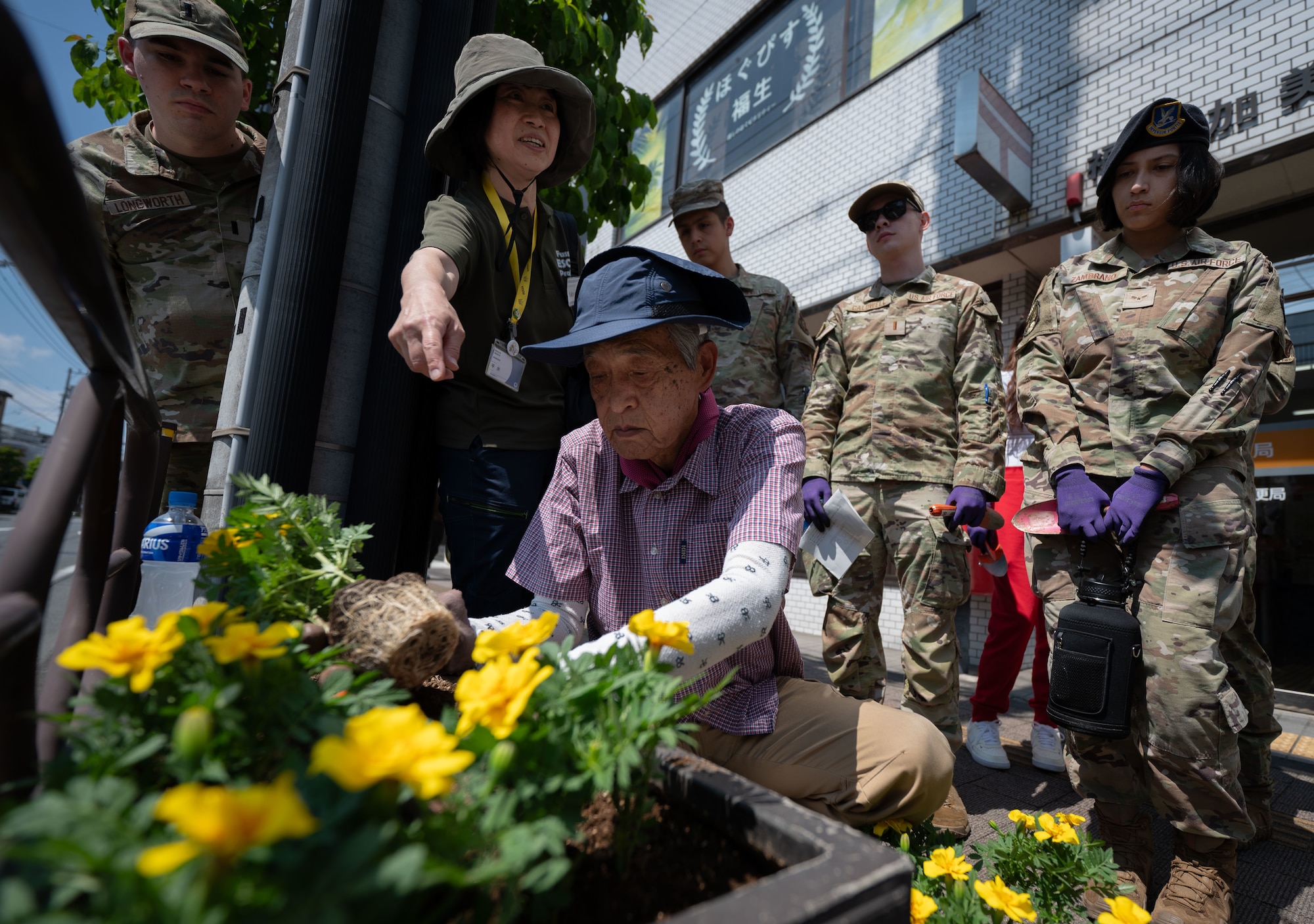 Airmen observe a demonstration on how to plant flowers.