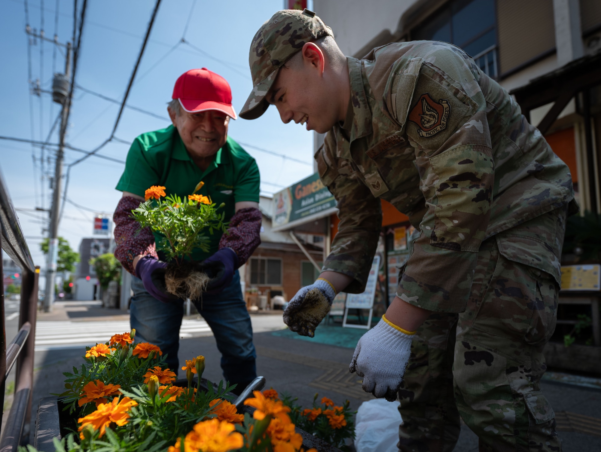An Airman and volunteer plant flowers.