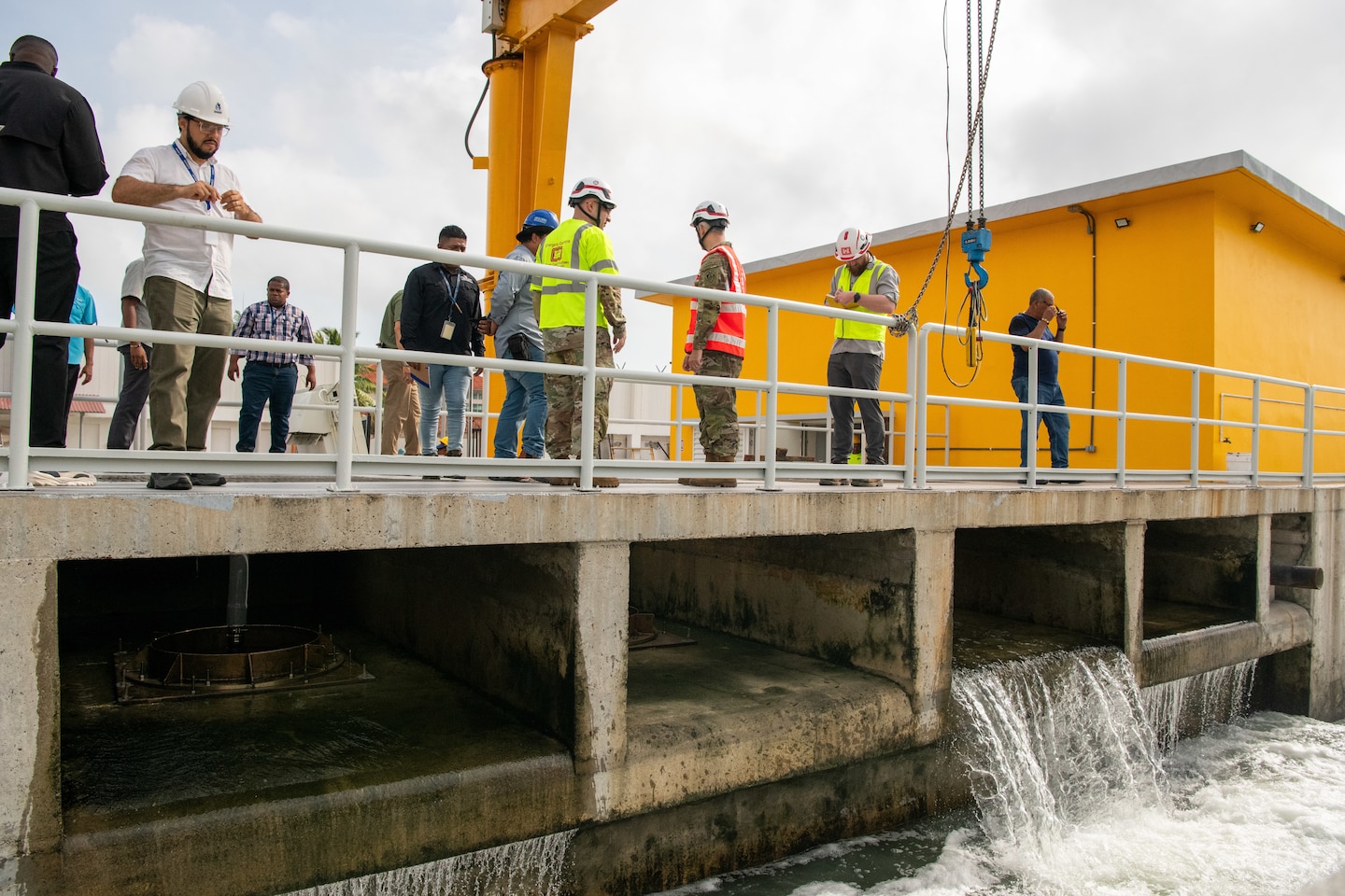 Men stand on a structure with water flowing underneath.