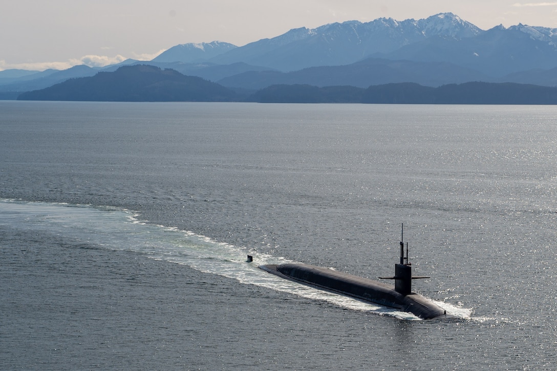 A submarine at sea with mountains in the background.