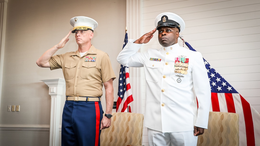 Marine Corps Col. Luke Watson, commanding officer, Blount Island Command, and Navy Chief Petty Officer Willie Newson render a salute during a retirement ceremony May 9 in the Ocean Breeze Conference Center at Naval Station Mayport in Florida. Newson, from Milwaukee, Wisconsin, served for 20 years. His assignments included deployments in support of Operation Iraqi Freedom and Operation Enduring Freedom. He most recently served as Navy senior enlisted leader, leading chief petty officer of medical materiel and security manager at Blount Island Command.