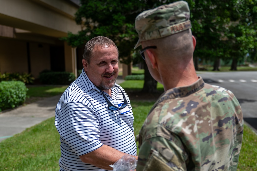 A man smiles as he shakes the hand of a man in an Air Force uniform.