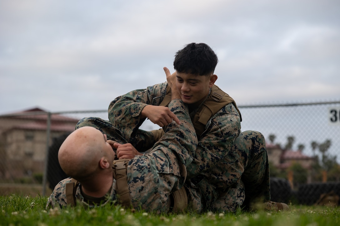 U.S. Marine Corps Capt. Mark Hamilton, bottom, assistant logistics officer, and Sgt. Alex Abuan, a data systems administrator, both with the 11th Marine Expeditionary Unit, I Marine Expeditionary Force, discuss proper technique for executing an armbar from the mount during a Marine Corps Martial Arts Program (MCMAP) course at Marine Corps Base Camp Pendleton, California, May 7, 2025.