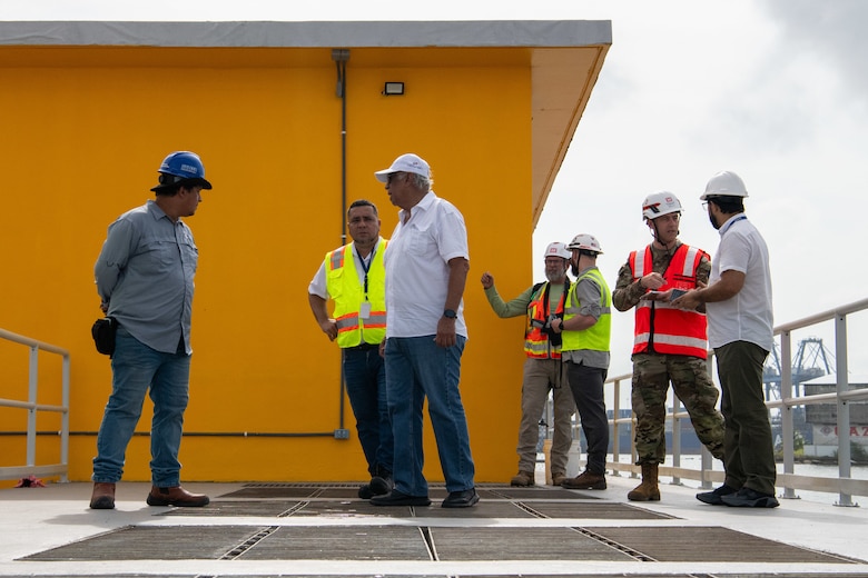Members of the Army Corps of Engineer’s Forward Engineer Support Team talk in small groups. Some are wearing hard hats and reflective vests.
