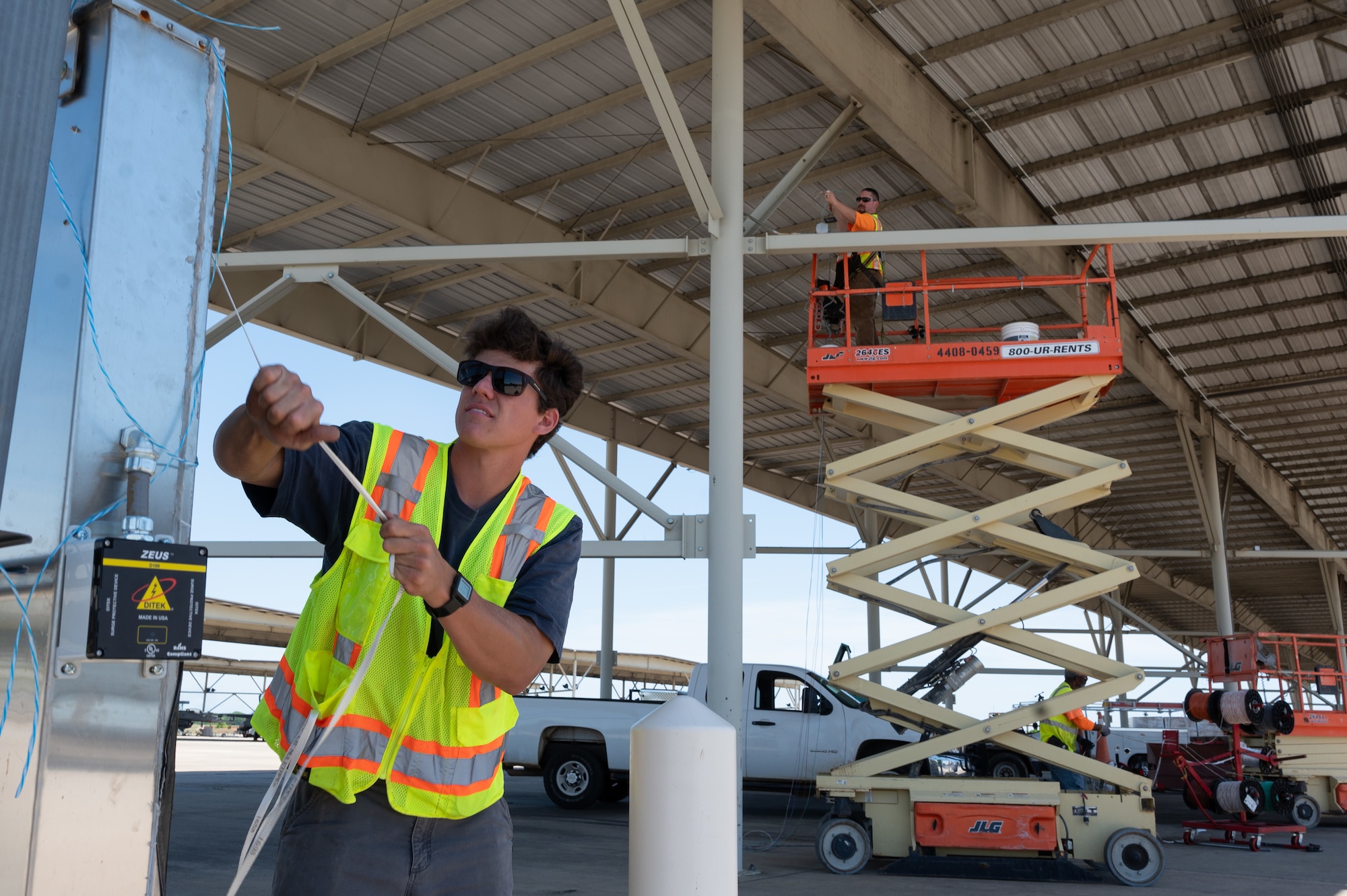 SB Ducom, a contractor supporting the 20th Civil Engineer Squadron, installs wiring for new LED fixtures under an aircraft sunshade at Shaw Air Force Base, S.C., May 1, 2025. The effort is part of a base-wide modernization aimed at boosting energy resilience and reducing long-term maintenance demands. (U.S. Air Force photo by Staff Sgt. Terry Clyburn)