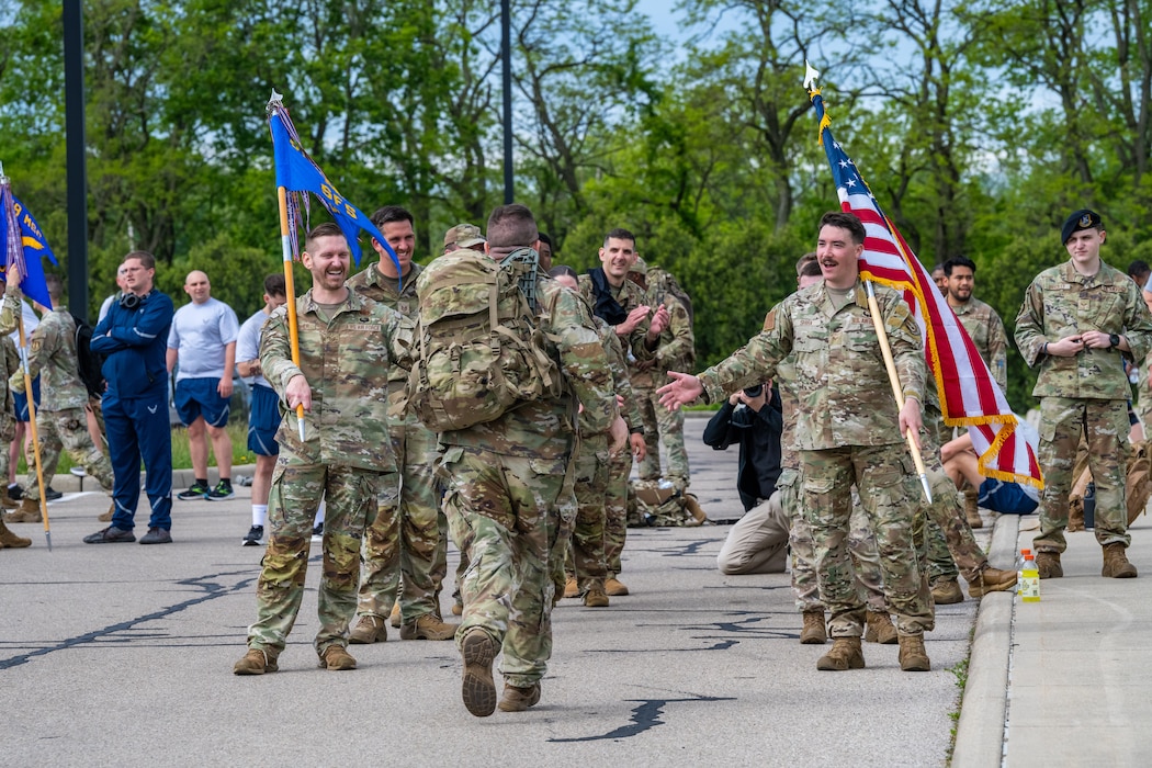 A large group of military members cheer on as others run through the middle
