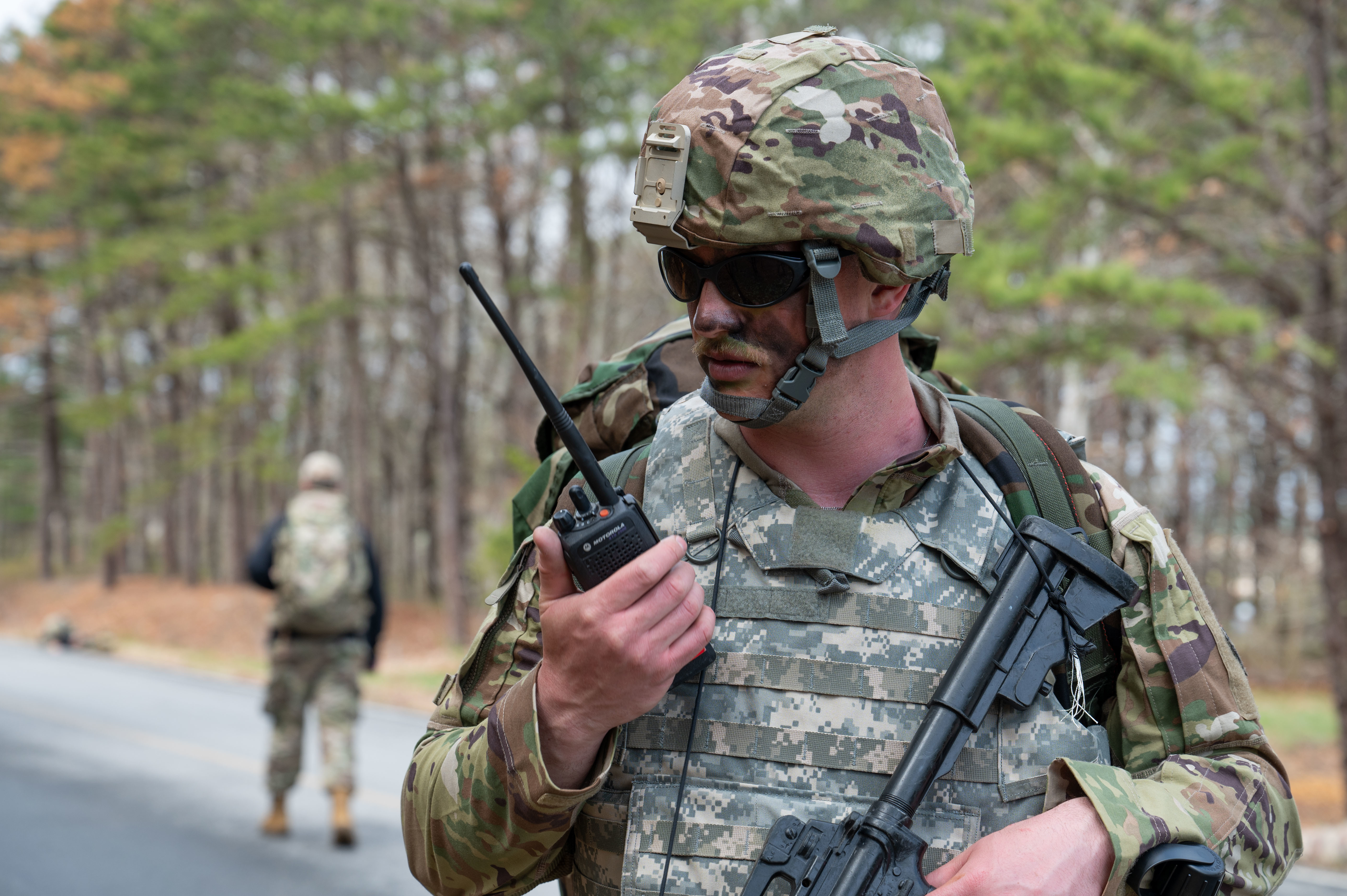 U.S. Air Force Staff. Sgt. Trenton DeTerra, a pavements and construction equipment specialist with the 102nd Civil Engineer Squadron, speaks into a radio during a tactical ruck march on Otis Air National Guard Base, Massachusetts, May 2, 2025. The 102nd Communications Squadron conducted radio training with all members of the 102nd Mission Support Group during Exercise Iron Nomad, a three-day, large-scale operation designed to simulate the rapid establishment of a forward operating location under simulated wartime conditions. (Air National Guard photo by Senior Airman Julia Ahaesy)