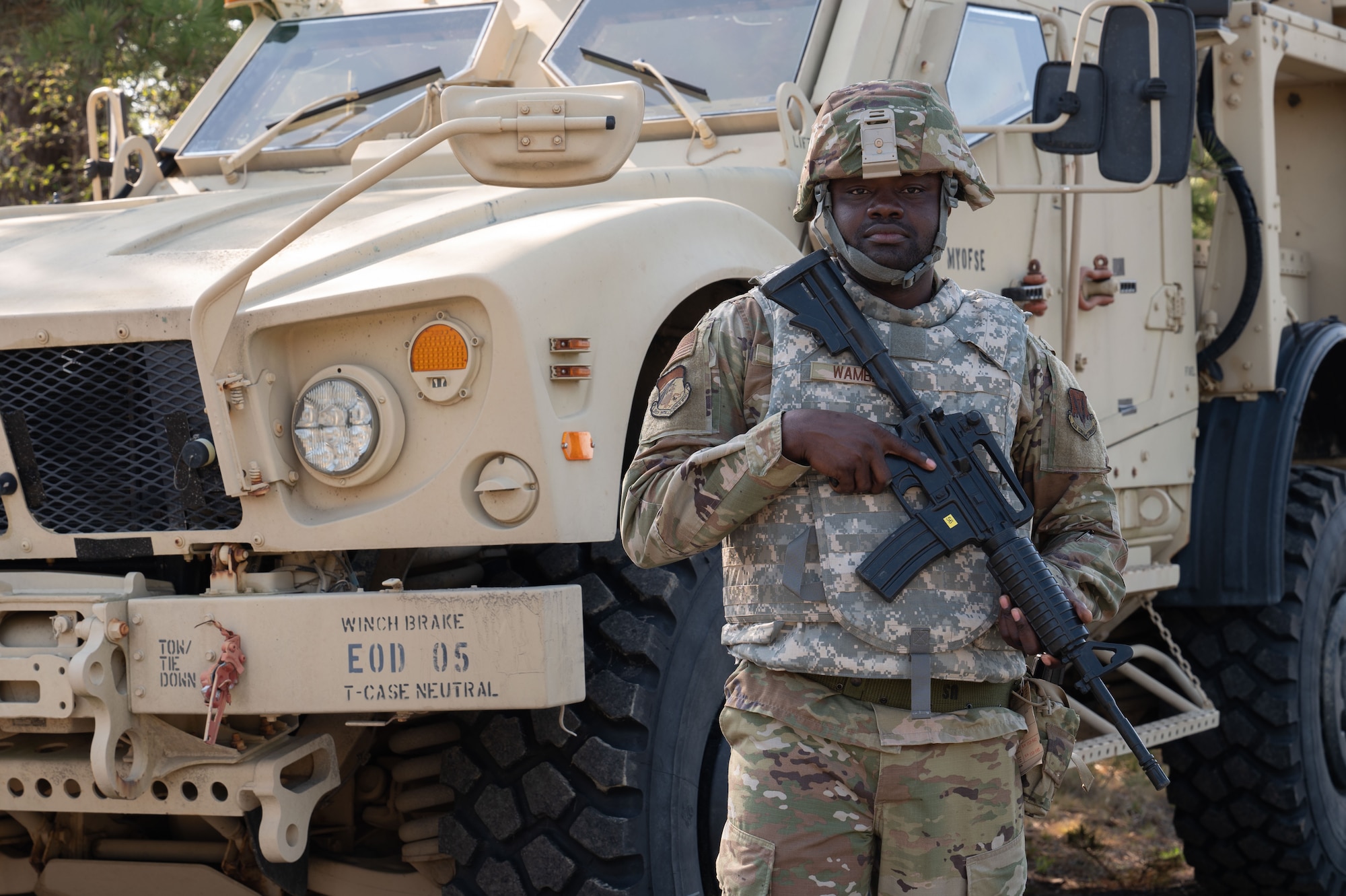 Airman stands in front of a tactical vehicle.