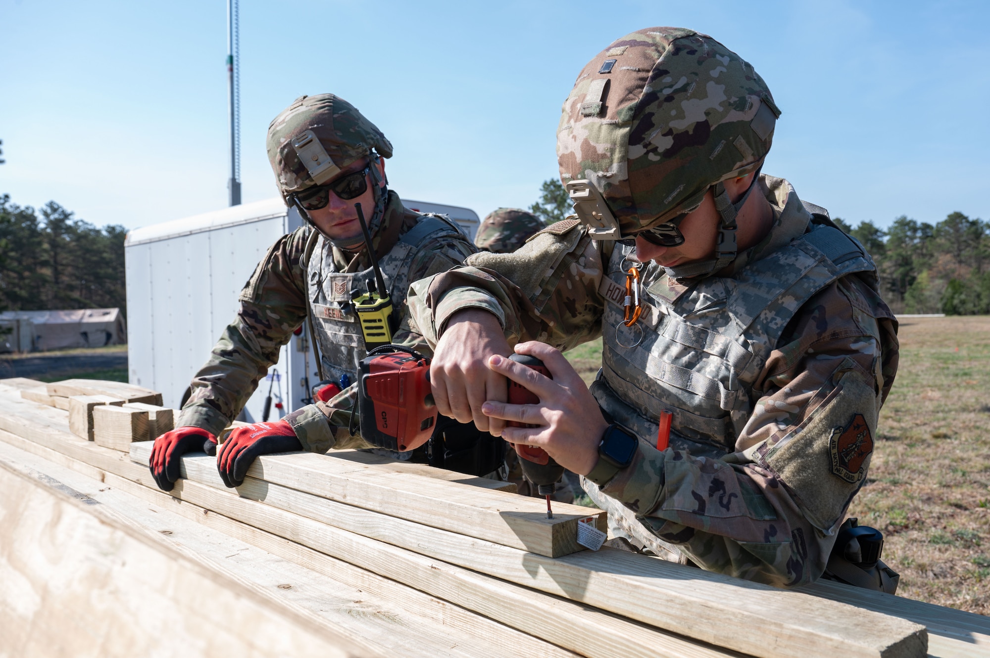 Airmen drill a screw into a piece of wood.