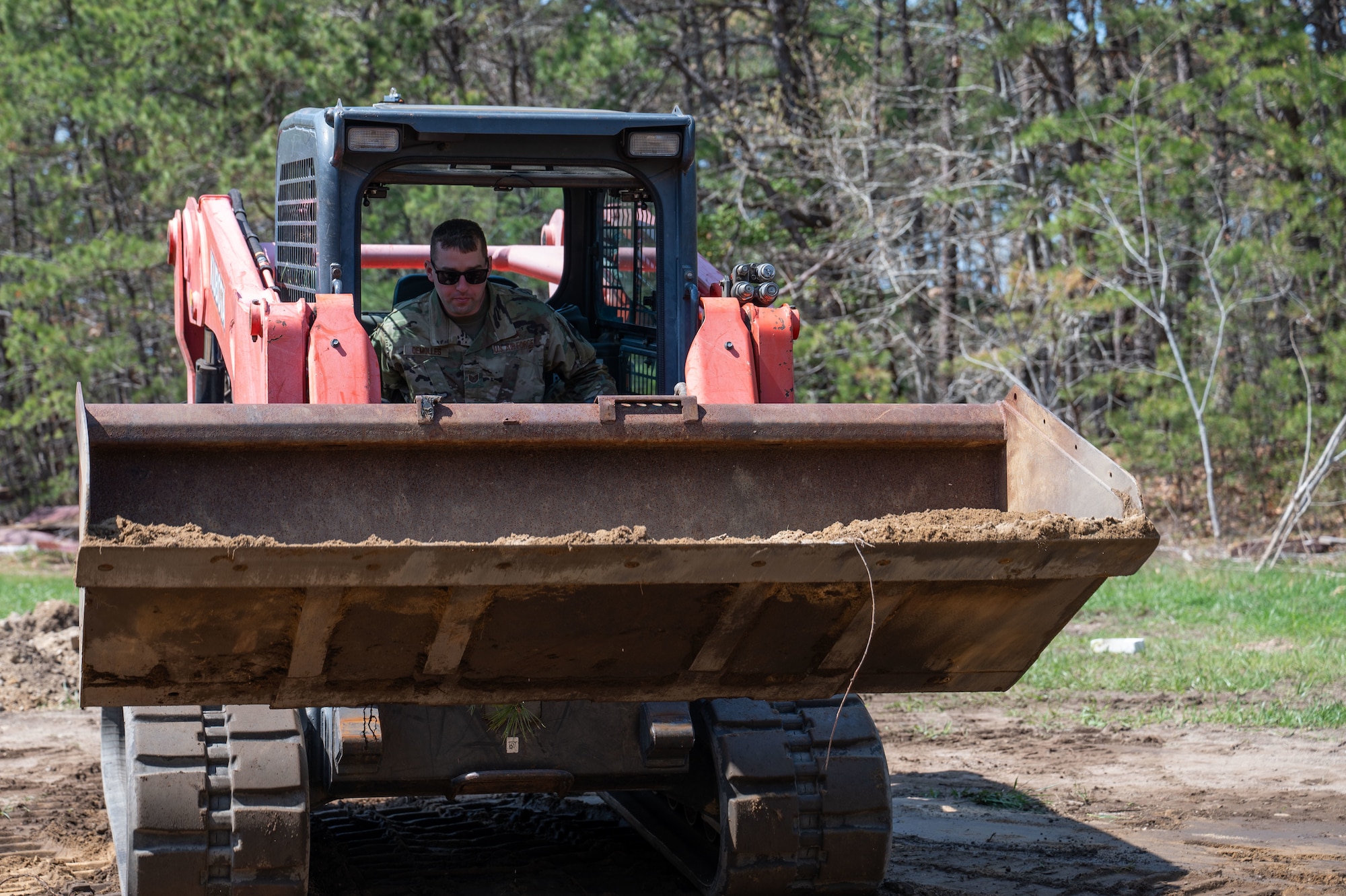 Airman drives a compact track loader.