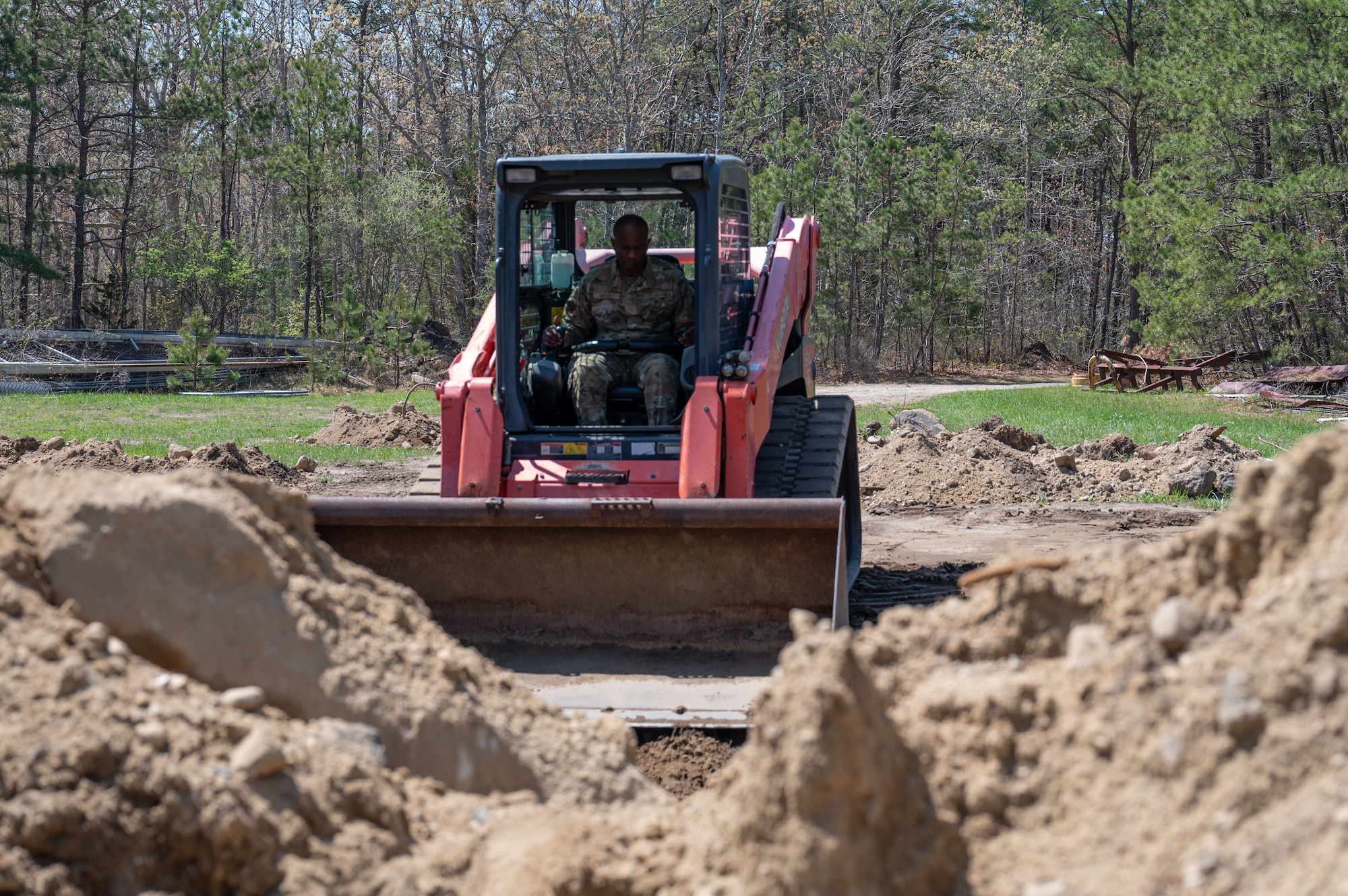 Airman drives a compact track loader.