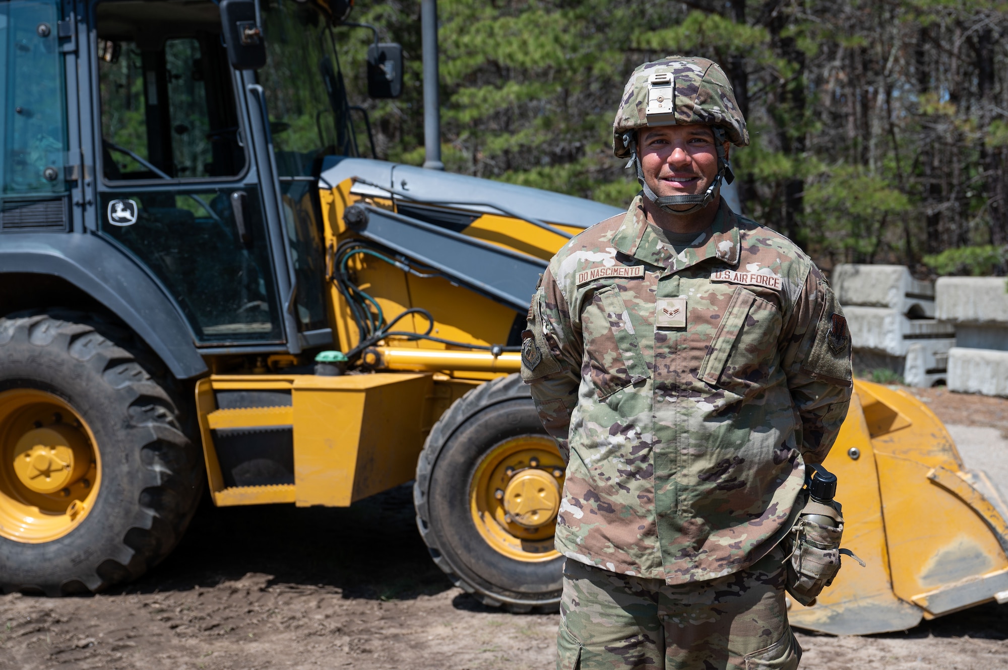 Airman standing in front of heavy equipment.