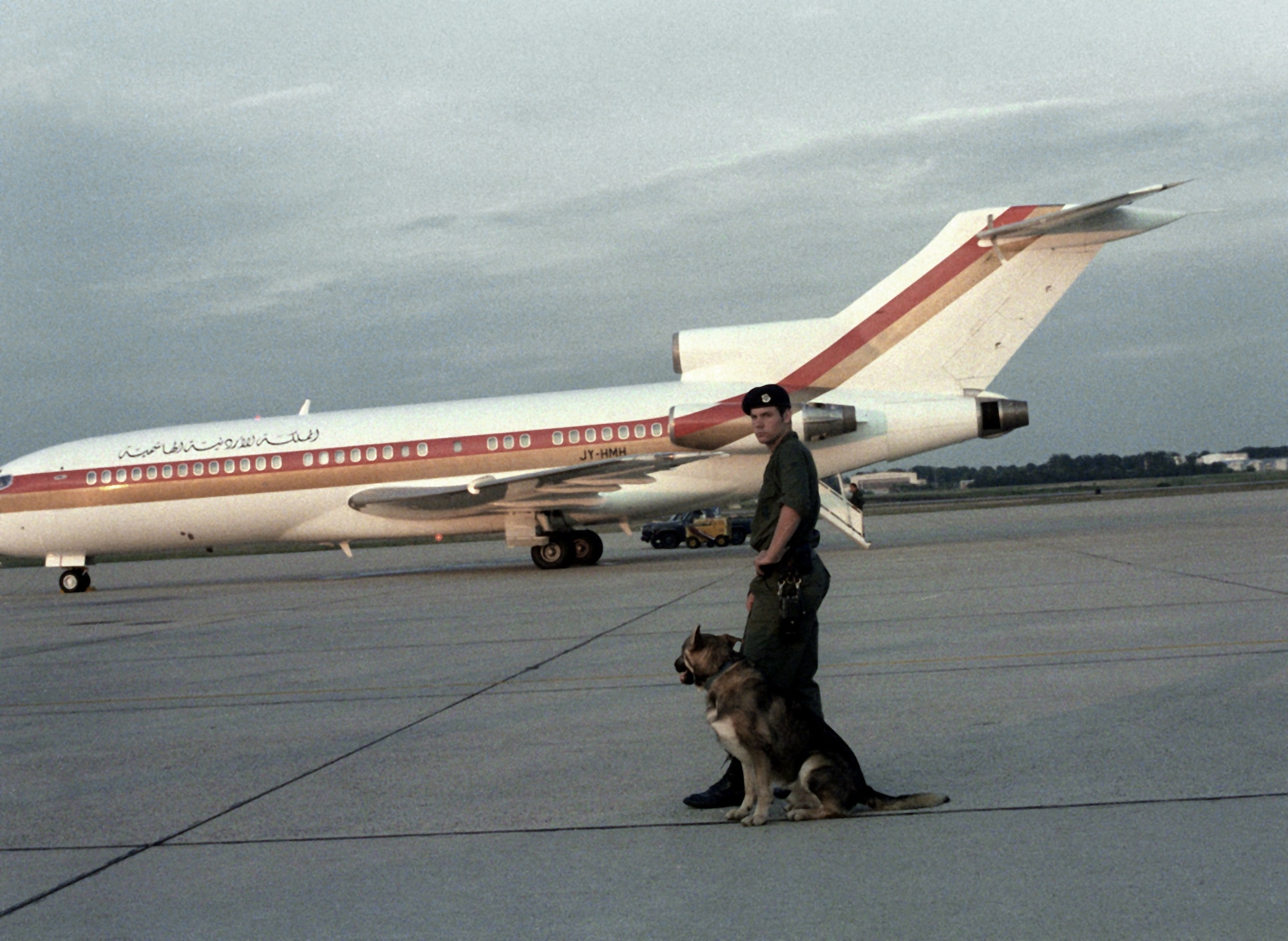 A security policeman of the 
76th Security Police Squadron 
and military working dog 
provide security as Jordanian
Airliner departs with King and 
Queen Hussein Bin-Talal on Jan. 1, 1980.
