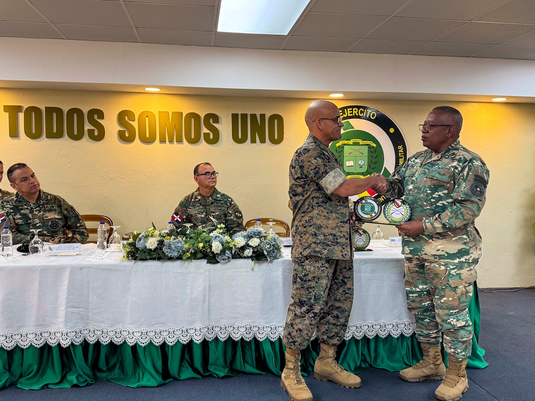 Military men in camouflage uniforms shake hands.