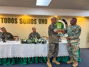 Military men in camouflage uniforms shake hands.