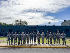 Military personnel sit at desks.