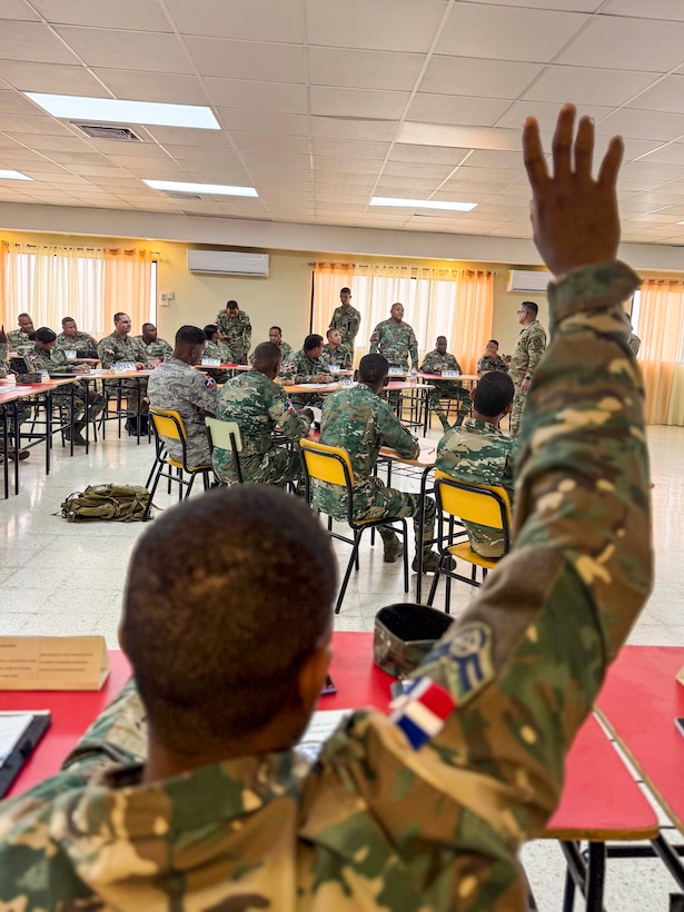 Military personnel sit at desks.