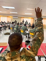 Military personnel sit at desks.