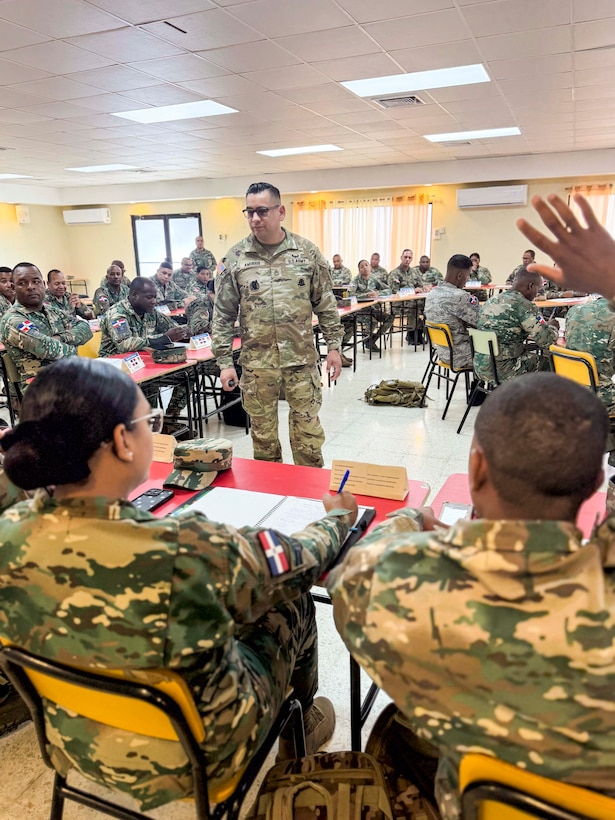 Military personnel sit at desks.