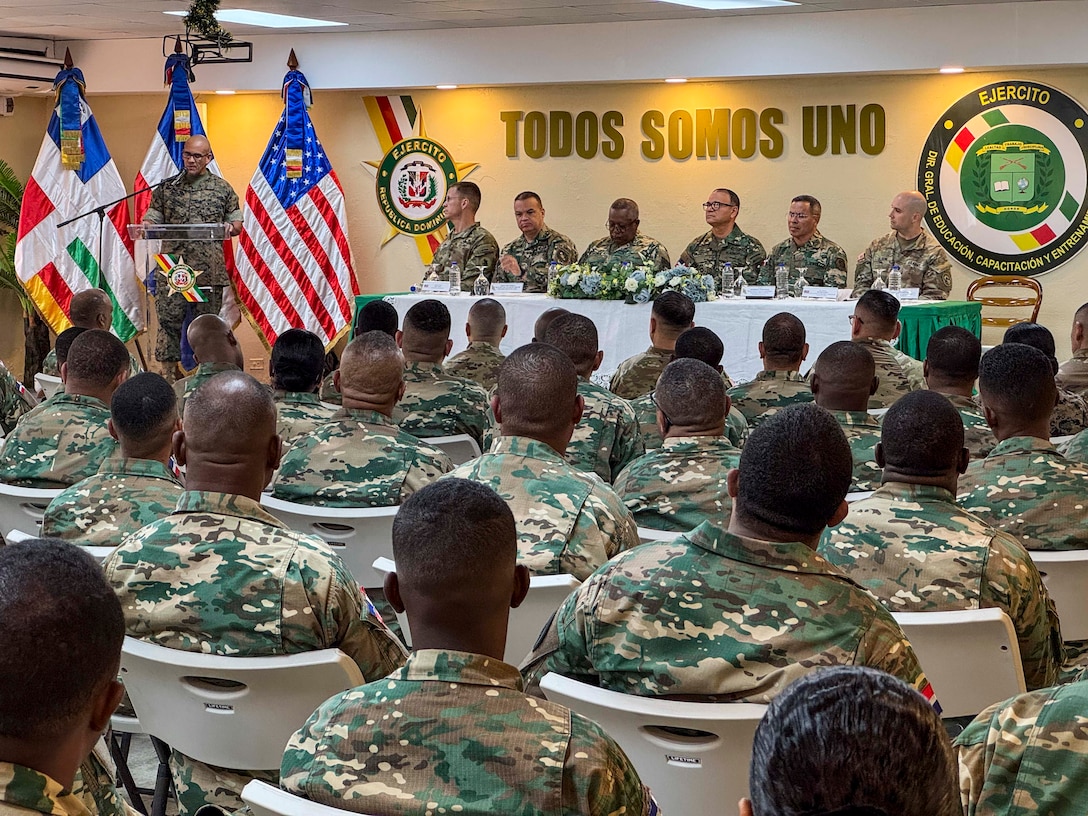 Military personnel sit at desks.