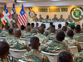 Military personnel sit at desks.