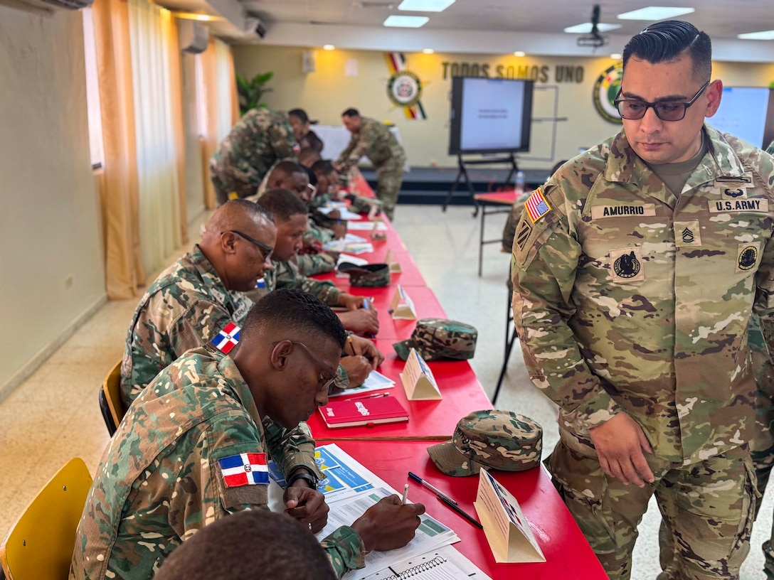 Military personnel sit at desks.