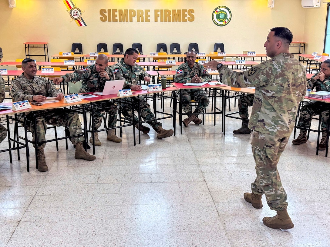Military personnel sit at desks.